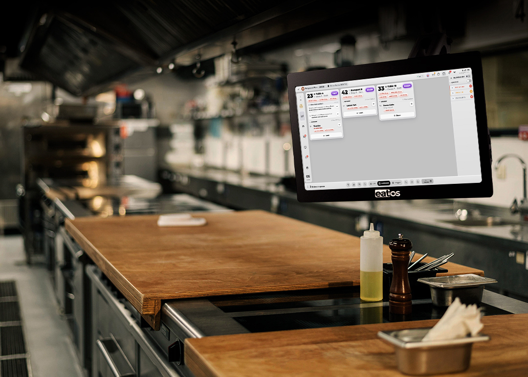 Chef working beside an eatOS Kitchen Display System screen